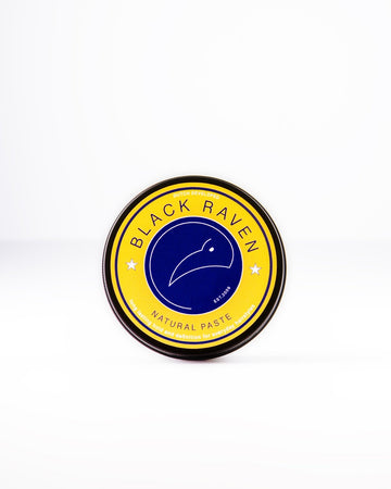 Black Raven Natural Paste for hairstyles, providing long-lasting hold and definition. Round yellow tin with a raven logo.