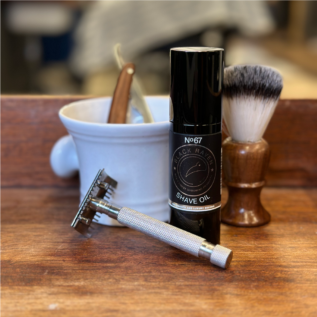 Black Raven No. 67 Shave Oil with razor, brush, and shaving bowl on wood surface.