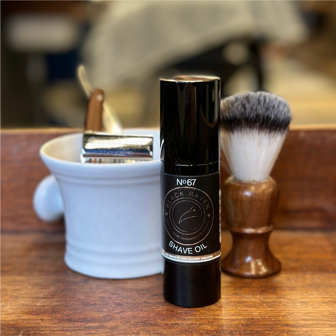 Black Raven No. 67 Shave Oil with razor, brush, and shaving bowl on wood surface.